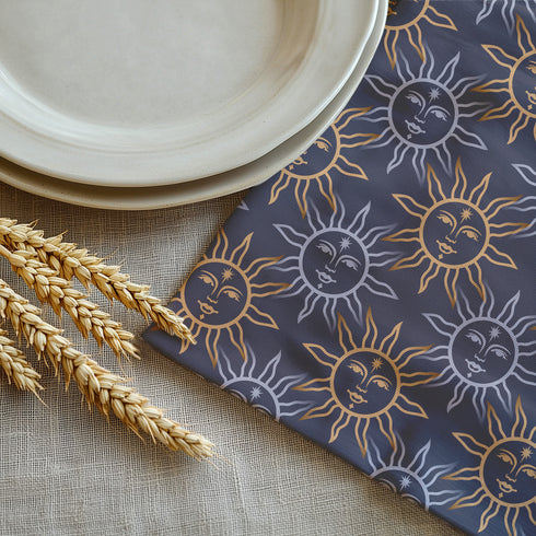 Four-piece cloth napkin set with celestial sun motifs in gold and silver on a deep navy background, made of durable, lint-resistant polyester.